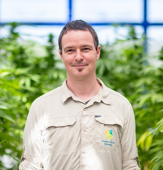 A man in a greenhouse smiling at the camera