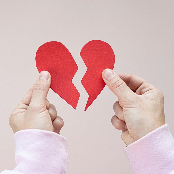 Two hands holding a broken heart