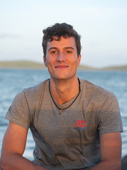 A man wearing a tshirt next to the ocean