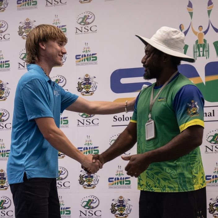 Student shakes the hand of a male coach at SINIS