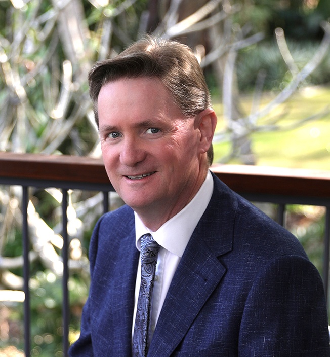 A man dressed in a blue suit and tie sitting outside