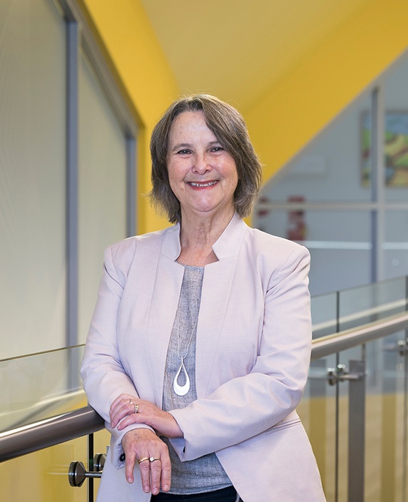 A woman in a jacket against a yellow and silver backdrop