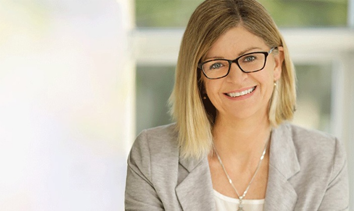 Headshot of woman with glasses and grey blazer