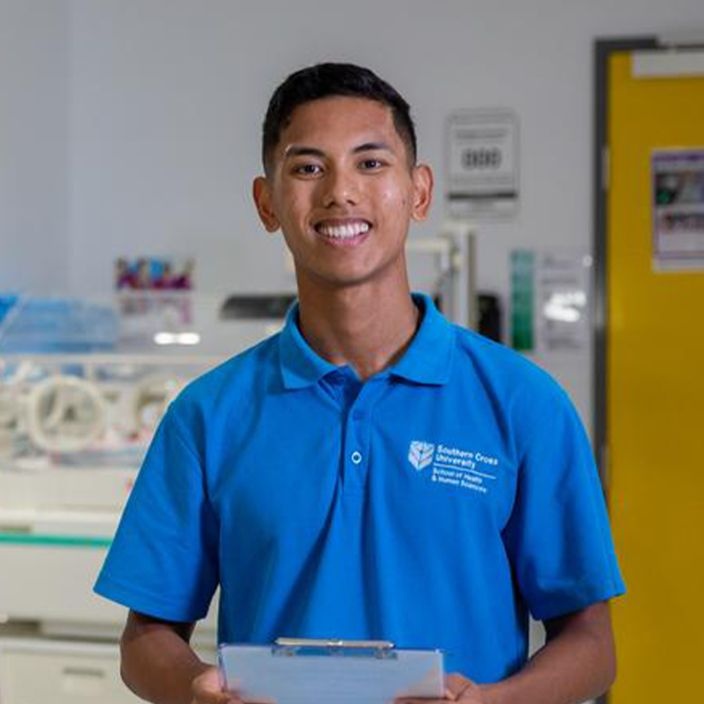 Registered nurse, John Palencia stands with a clipboard