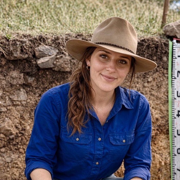 Girl in a hat smiling at camera in a soil pit