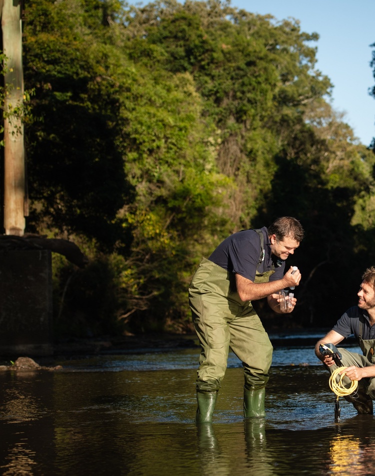 Two researchers sampling water from a river