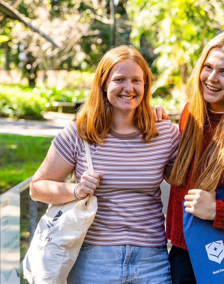 Two potential students on the Northern Rivers campus surrounded by greenery