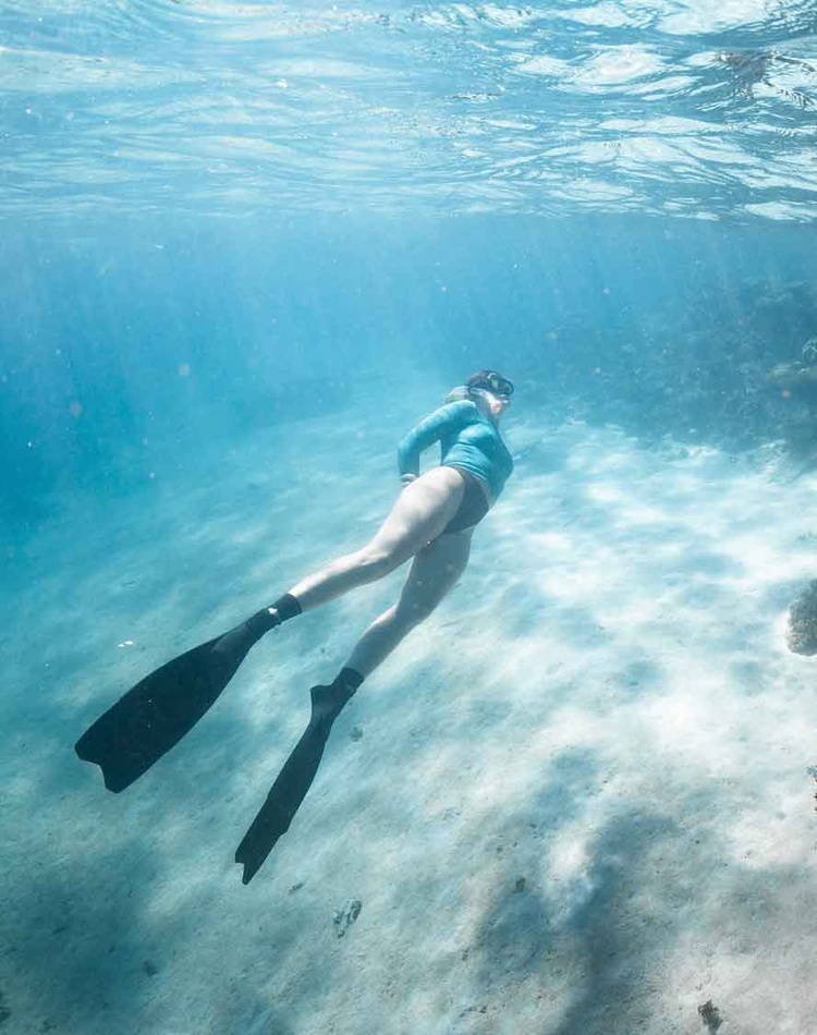 A woman swimming near a coral reef