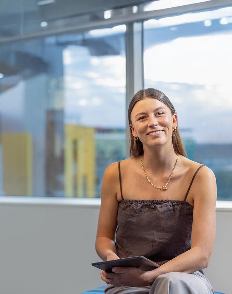 female sitting with view from Gold Coast campus in background - Marketing use atm only please