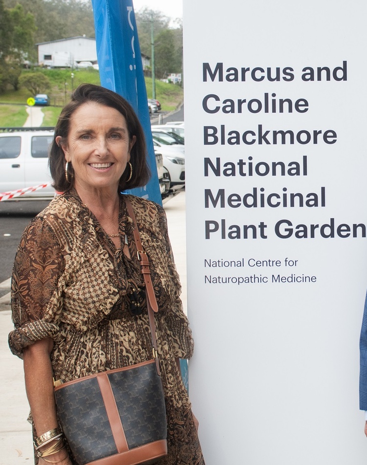 Two men and a woman in front of a sign that says Marcus and Caroline Blackmore Medicinal Plant Garden