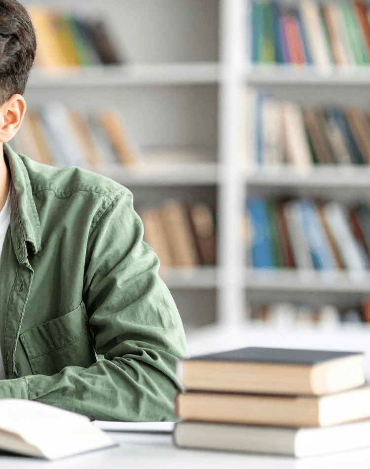 Student reading textbook and working on laptop - postgrad events banner