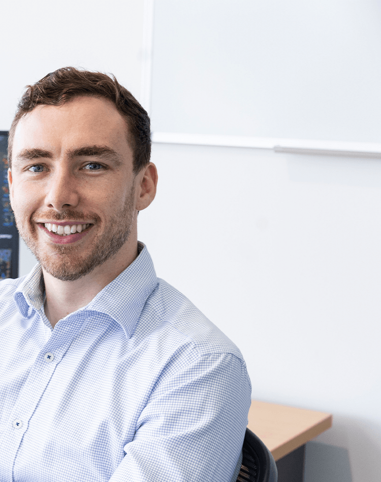 Man smiling at camera sitting at desk with video game on computer