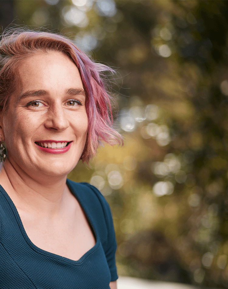 Woman in green shirt smiling with greenery in background