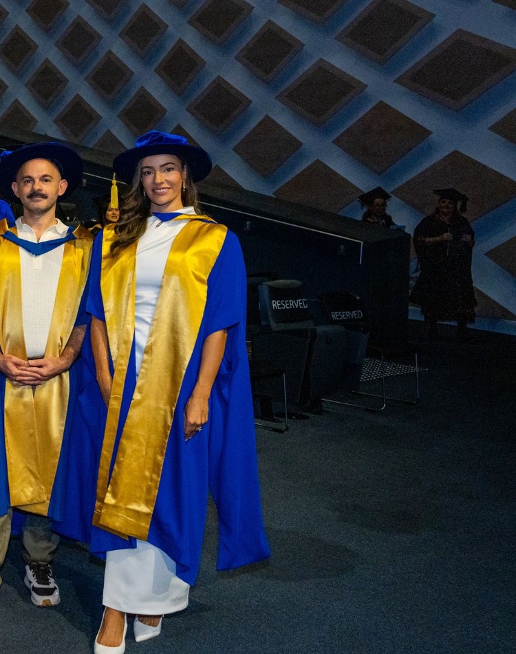 Men and women in graduation robes smiling at camera