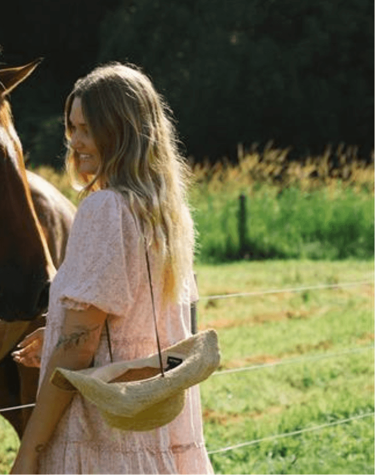 A woman, Scarlett Austin, stands beside a horse