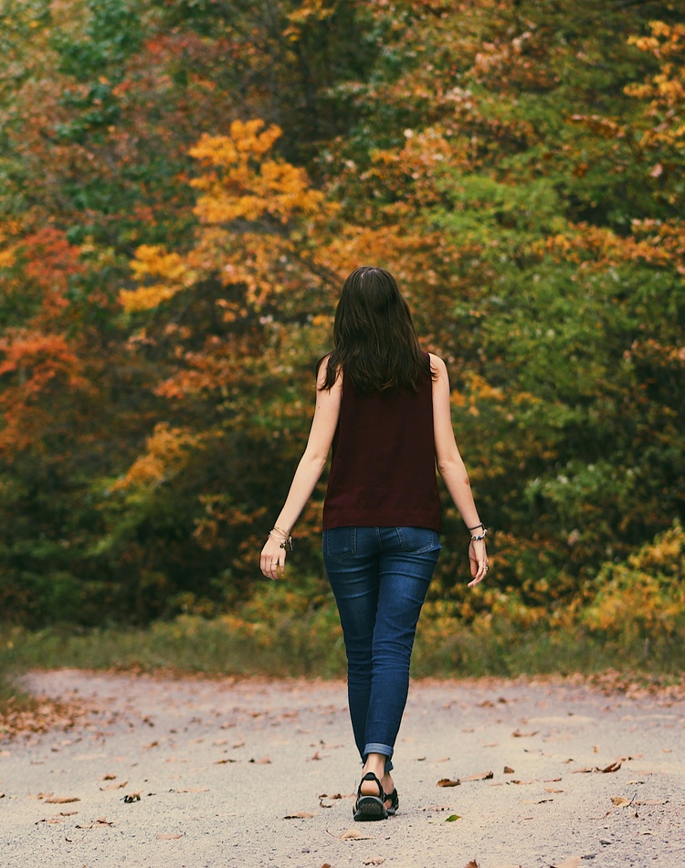 Woman walking away from camera on forest trail