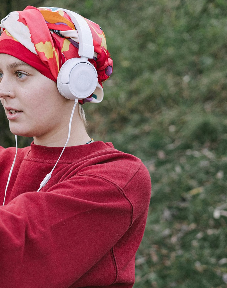 Woman recovering from cancer treatment wearing headphones and doing exercises