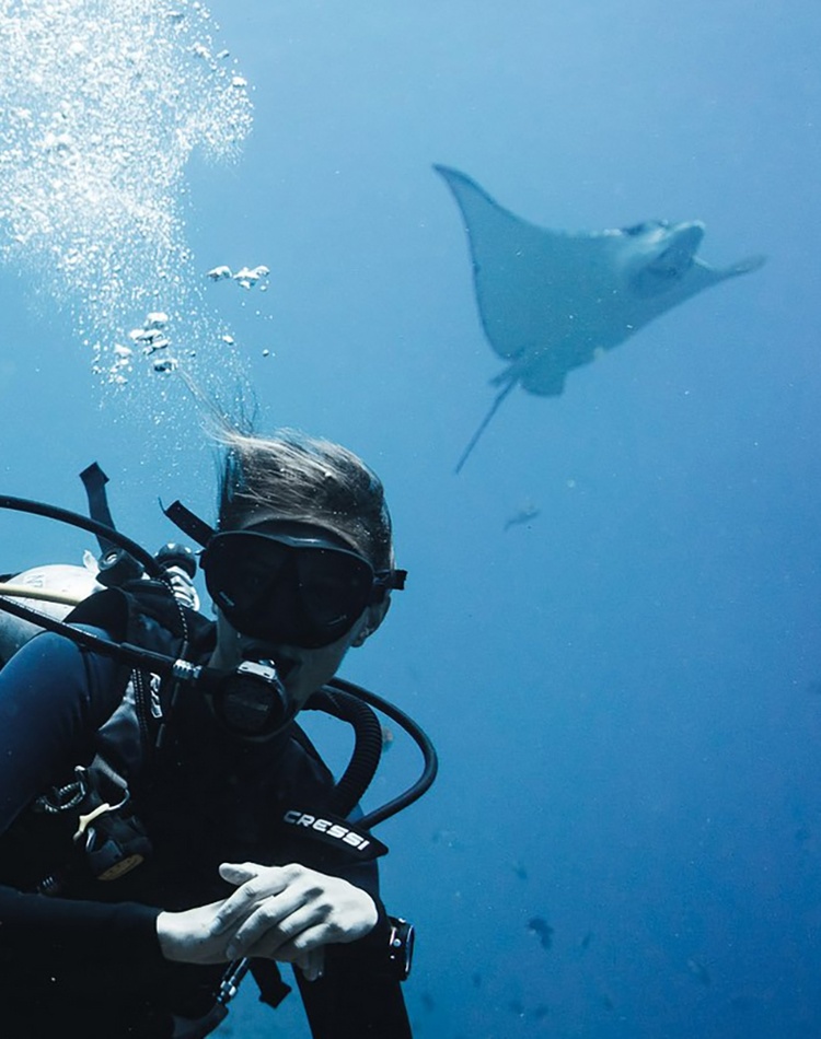A scuba diving under the water with a manta ray