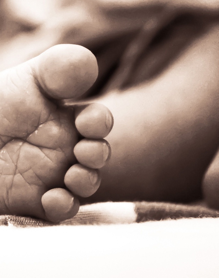 Monochrome close-up of a newborn's delicate foot on a soft surface