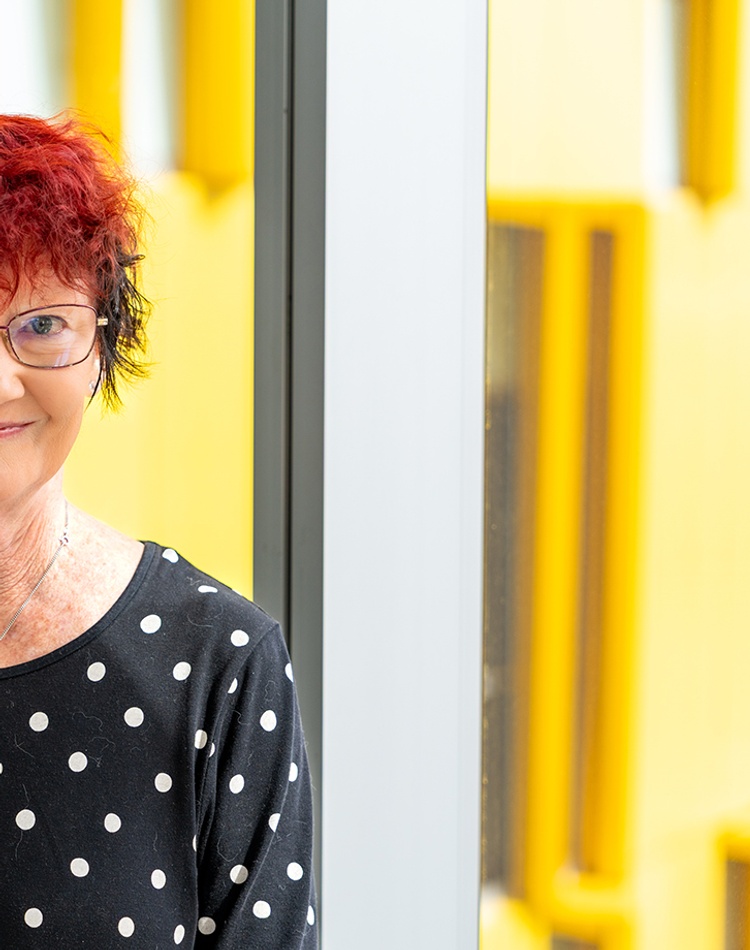 A woman looking at the camera against a modern yellow and glass background