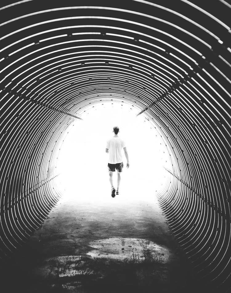 A silhouetted figure at the end of a dark tunnel