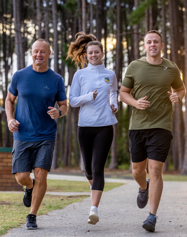 Three adults running in a park