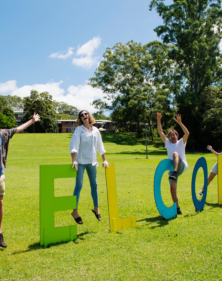 Five students and a welcome sign at Lismore campus