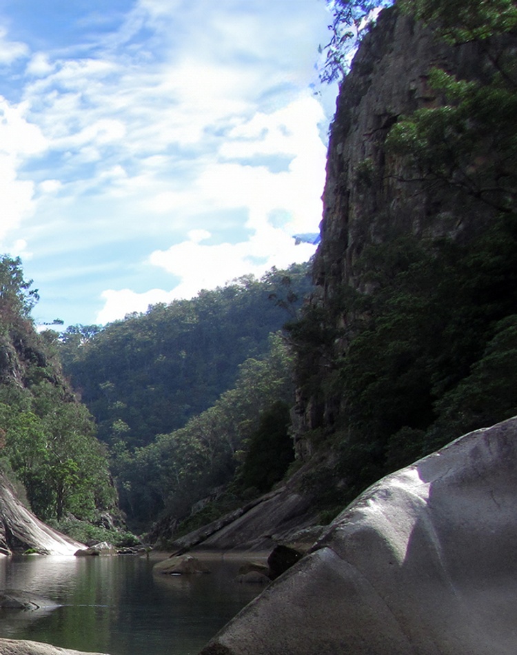 A steep valley with large boulders and a river running through it