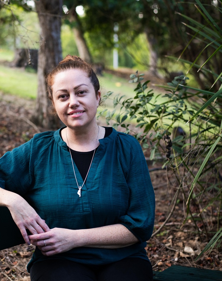 A woman sitting on a bench in a parkland setting