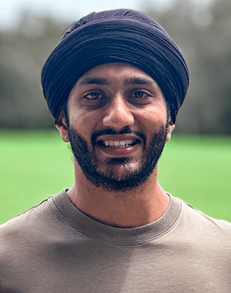 Student Gurpreet Singh smiling at camera on grassy field
