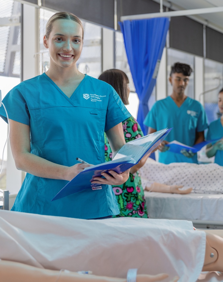Nursing student writes notes while students learn behind her