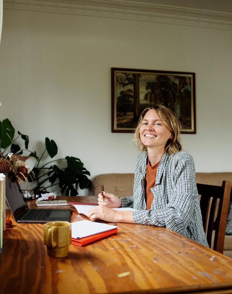 Woman smling at camera while writing in a book