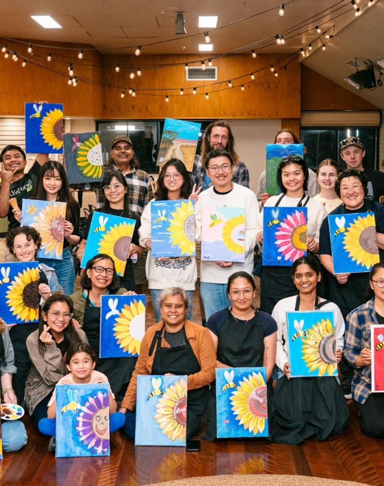 A group of students hold up their paintings at Lismore campus
