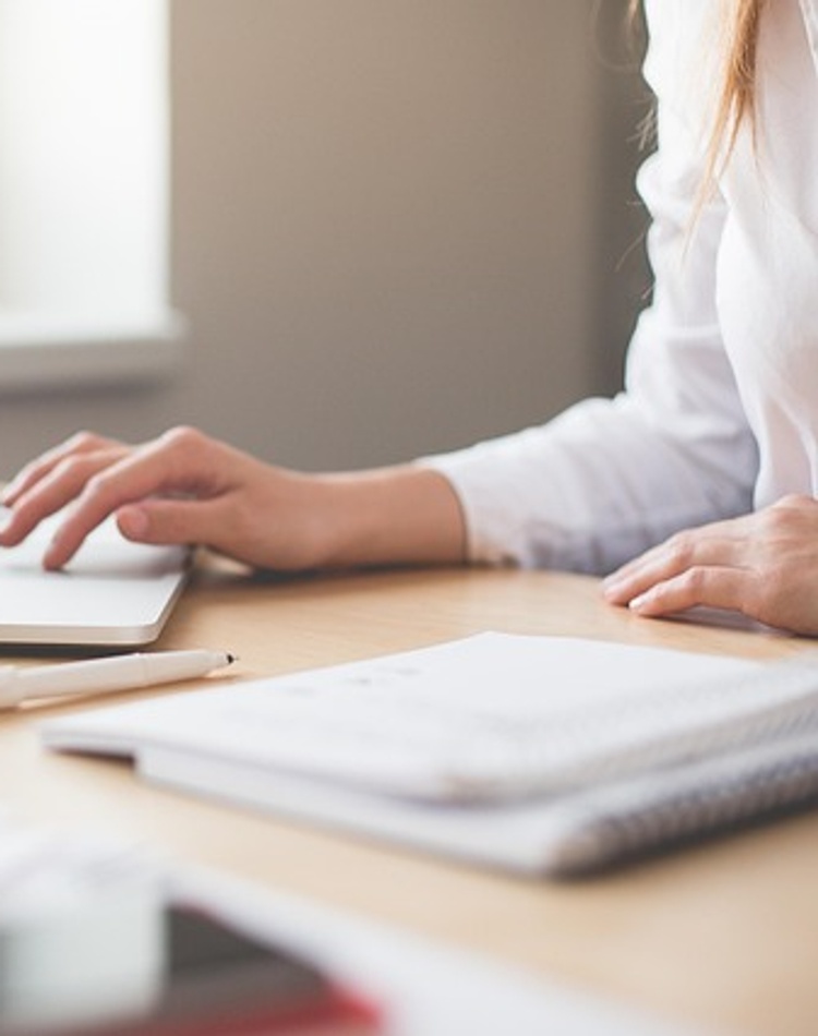 person typing on laptop keyboard with one hand