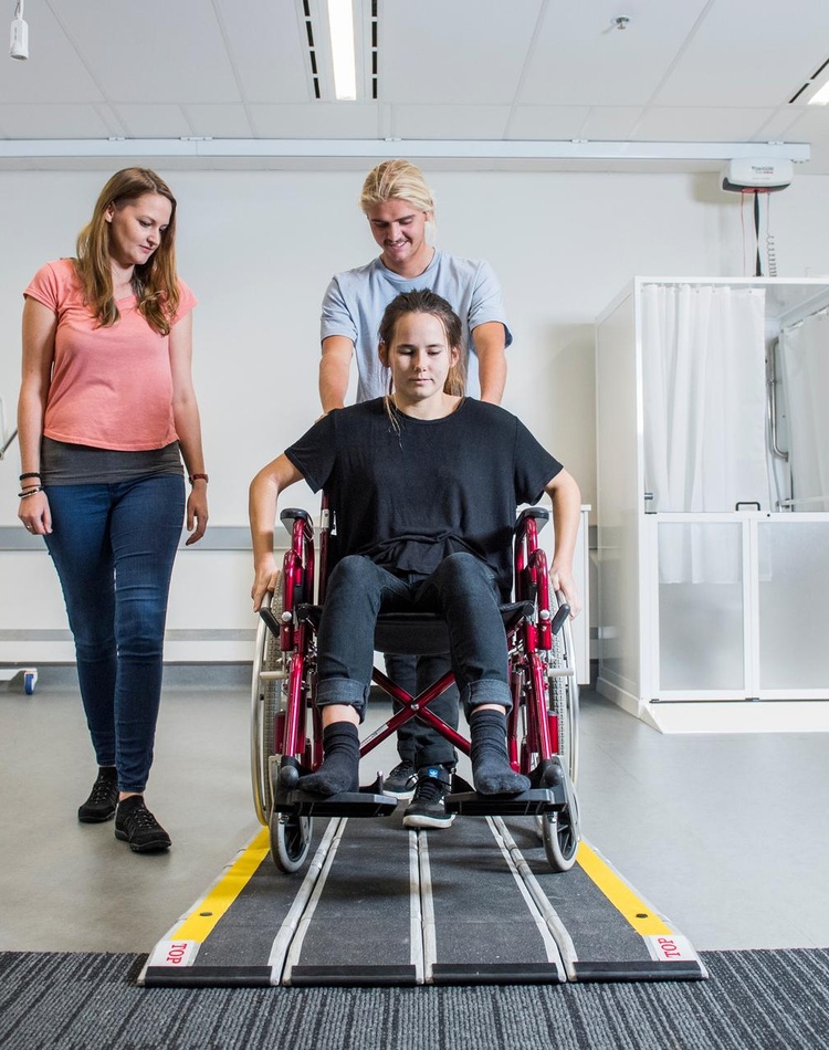 student pushing wheelchair for occupational therapy