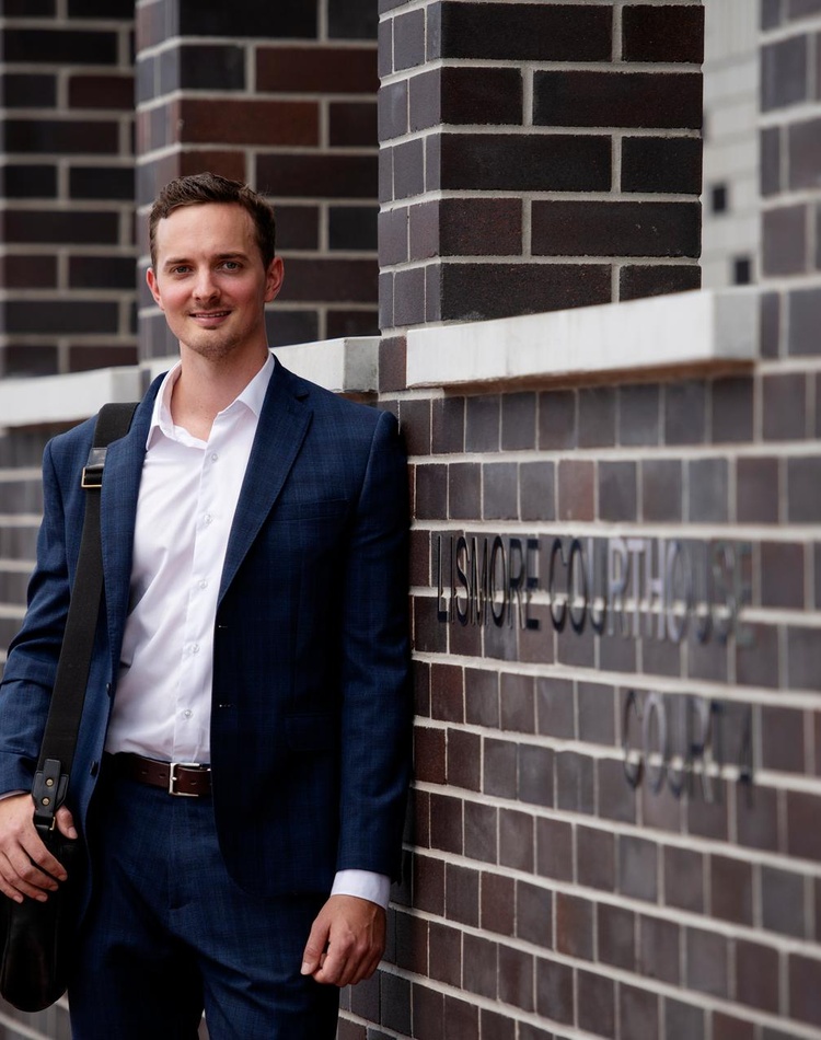 Student standing in front of course house in a suit
