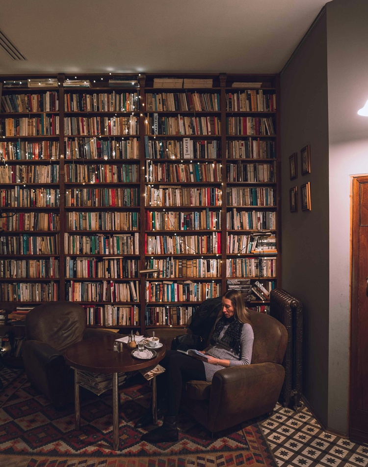 Person reading a book in a chair against wall of books