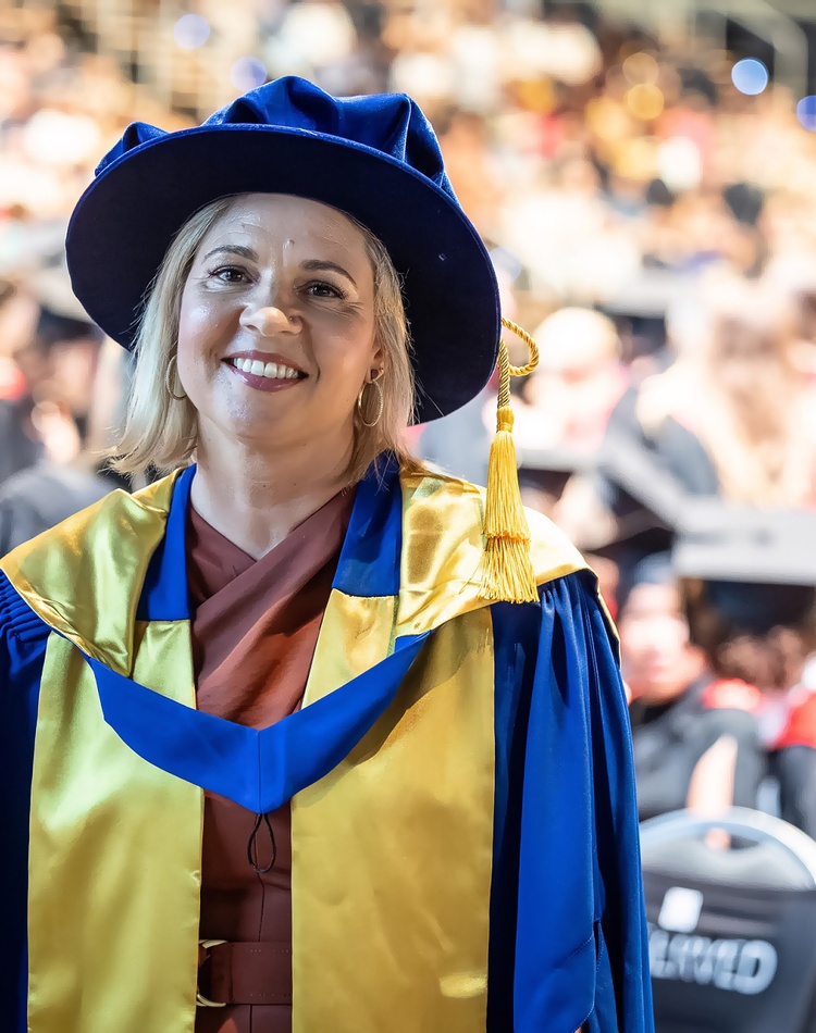 A woman in academic robes smiling at the camera