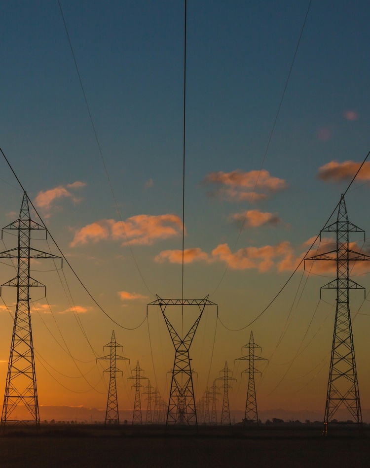 A series of power lines with a setting sun in the background
