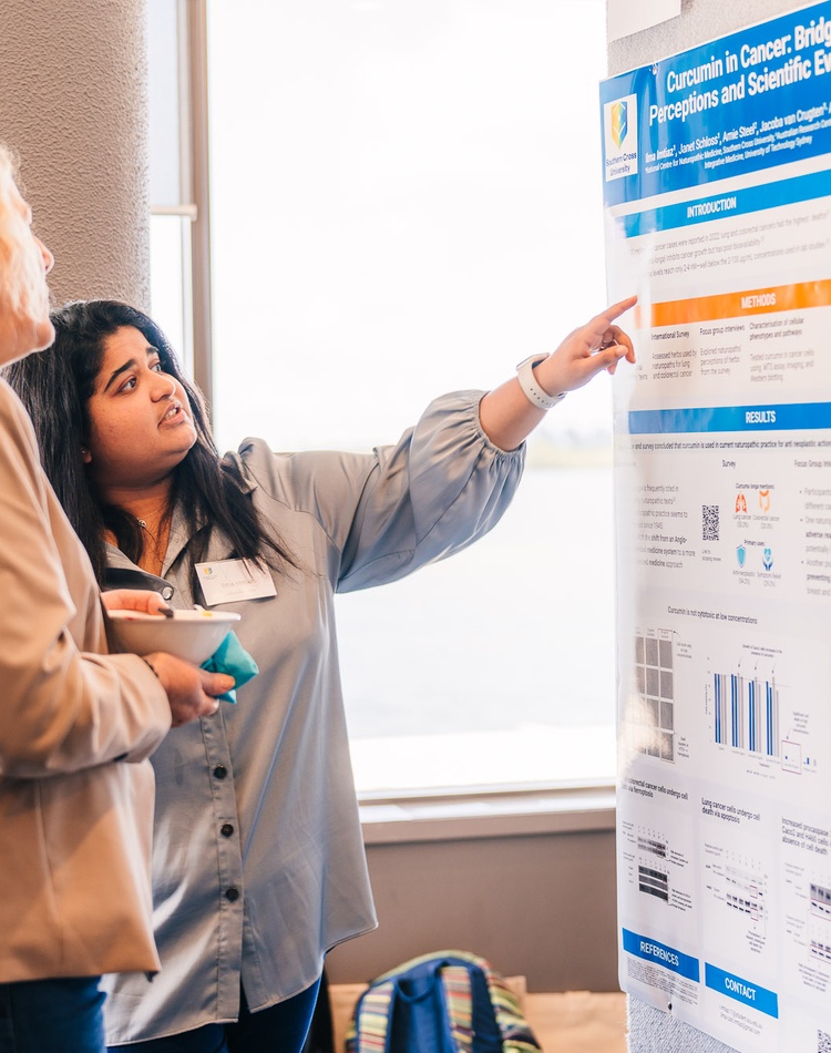 A student showing her project poster to a woman