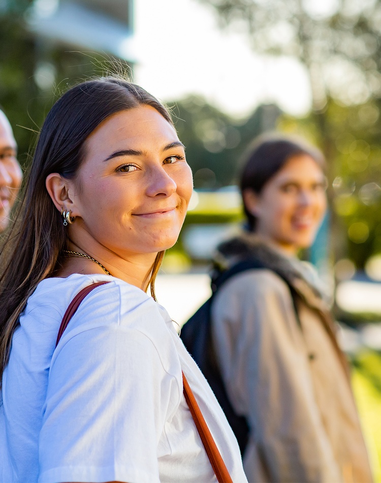 Female students looking back over her shoulder smiling with other students in background