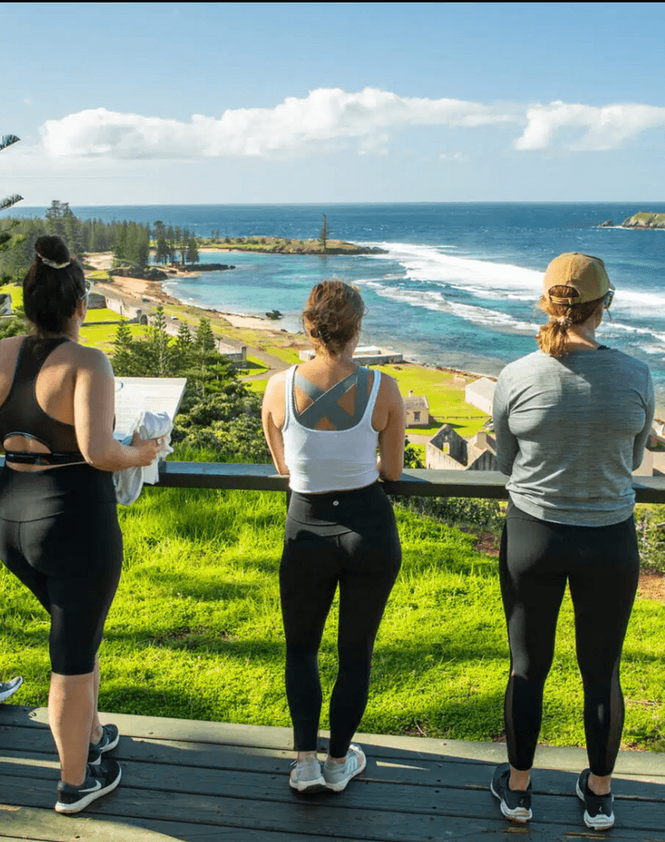 Three people in leggings gazing out to sea