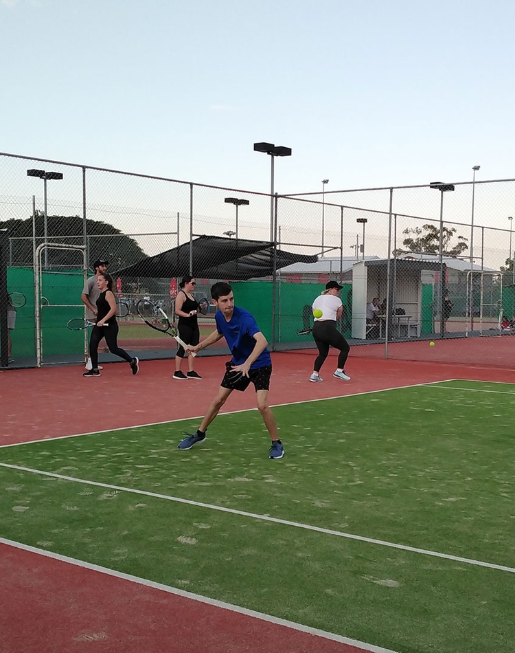 Students practising on tennis court