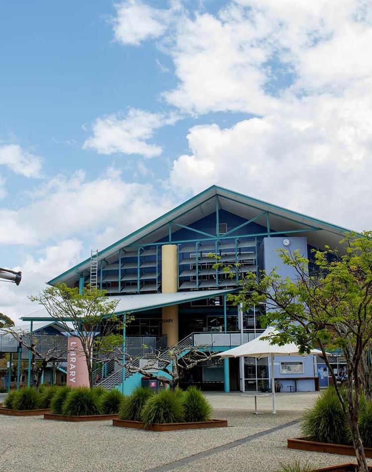 A wide angle view of the coffs harbour campus with green forested hills in the background