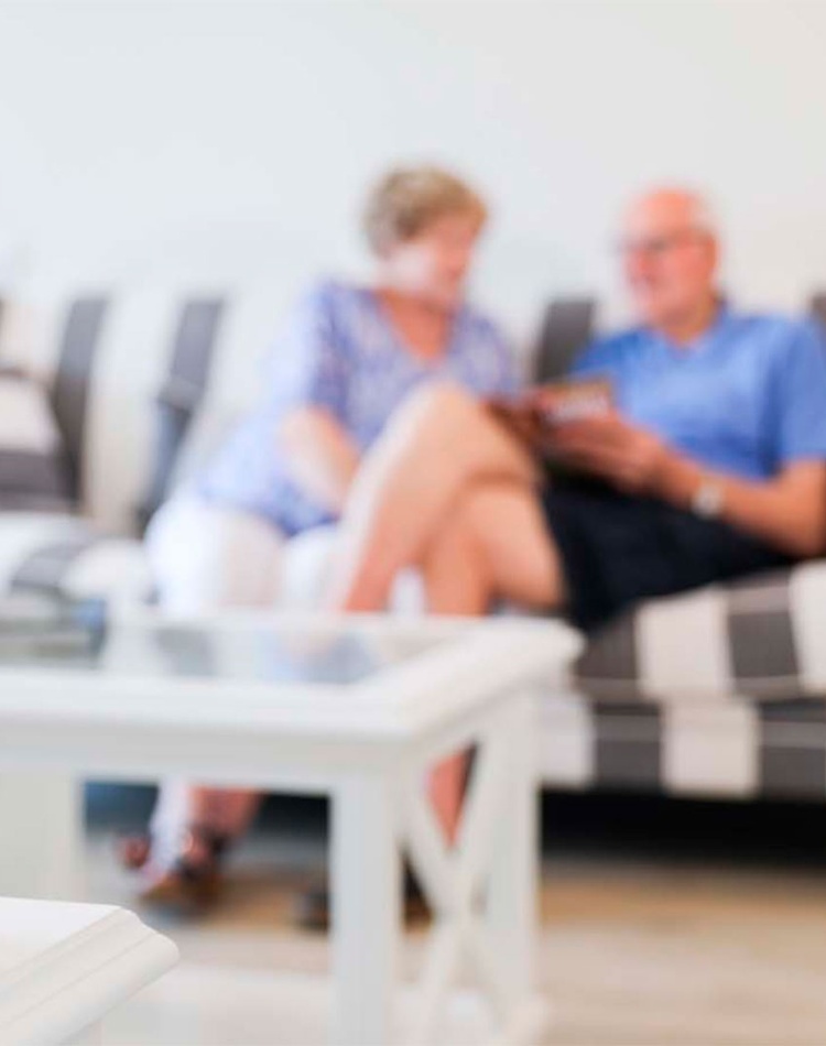 Smart device in foreground with blurred elderly couple in background