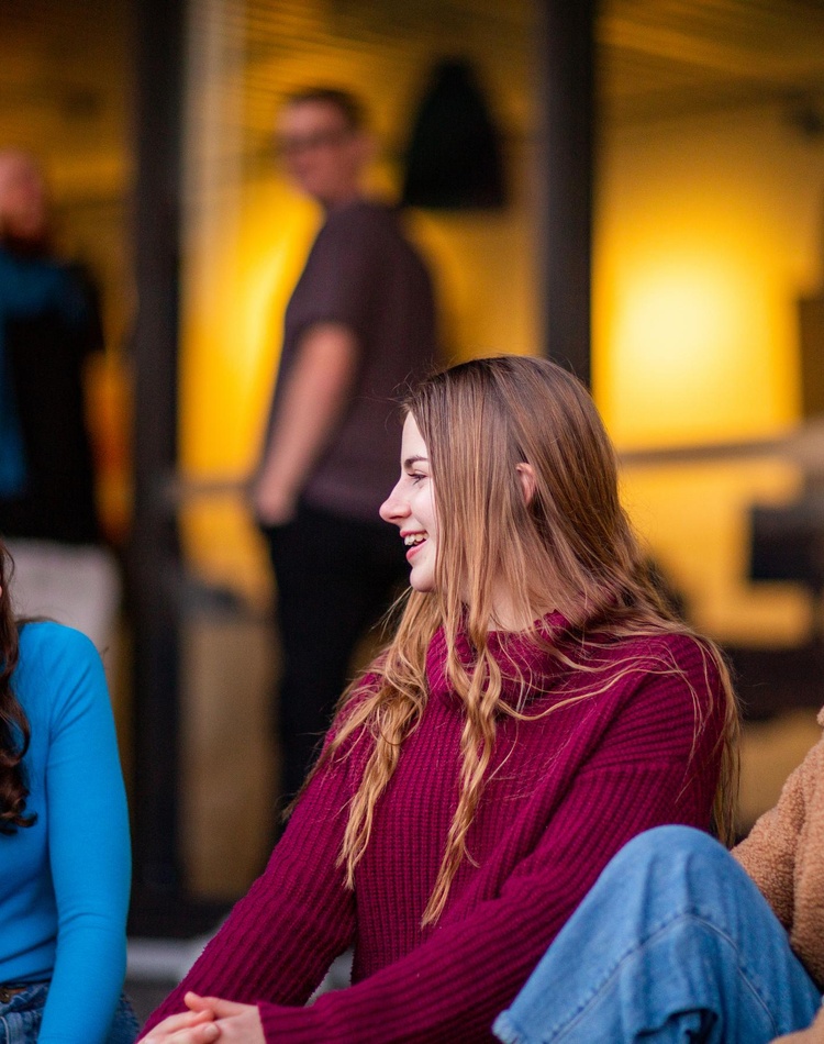 Three students sitting on a bench laughing