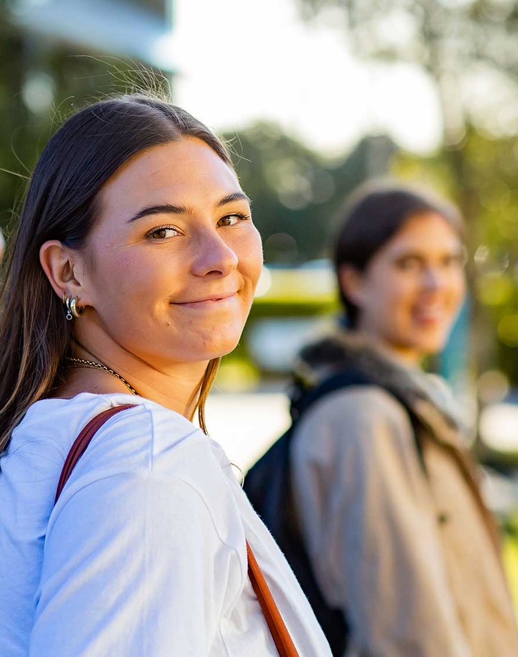 Female students looking back over her shoulder smiling with other students in background