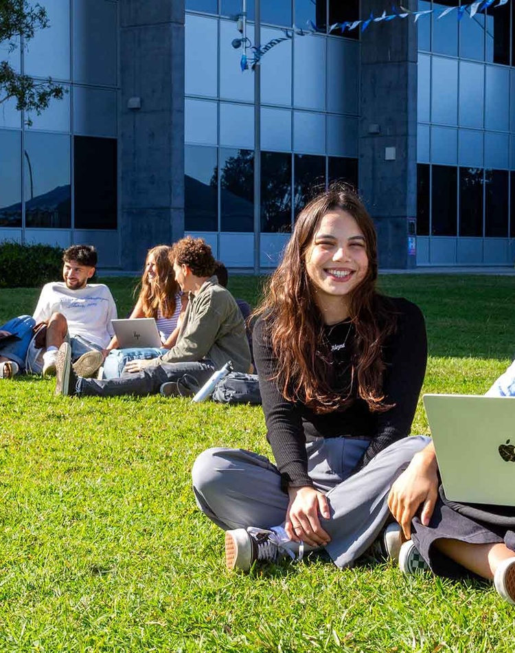 International students from Germany and Italy sitting on the grass with laptop
