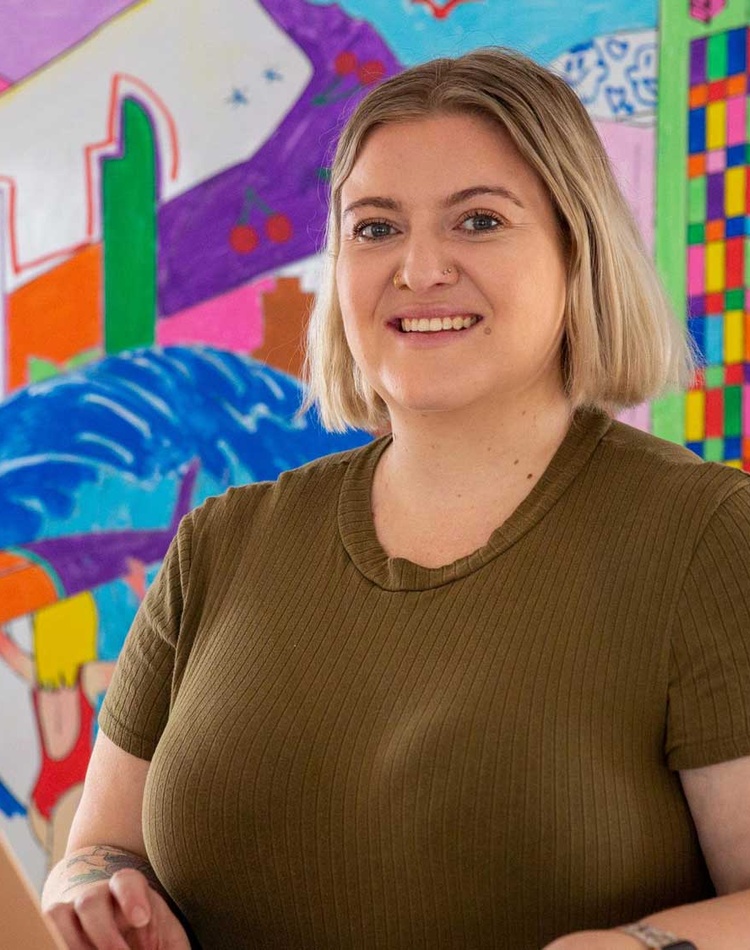 Student sitting at a table with a laptop smiling at the camera