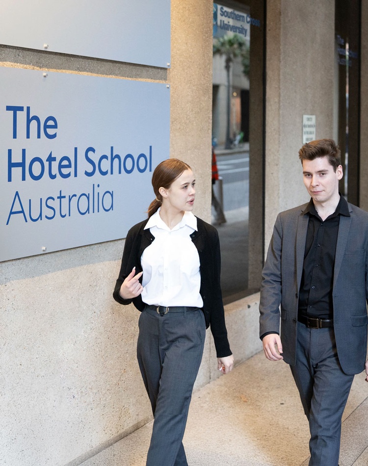 Students walking in front of sign Hotel School Australia